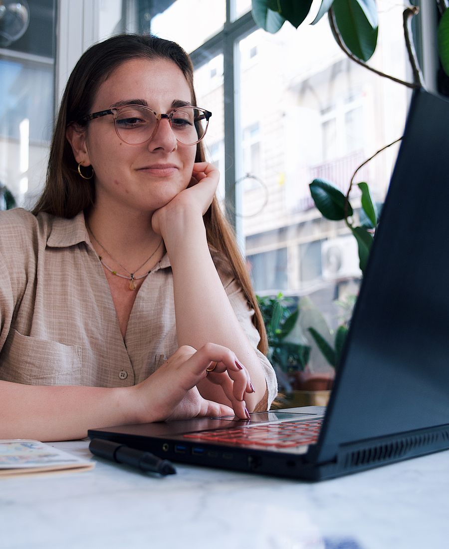 Laptopunun başında gülümseyen bir öğrenci